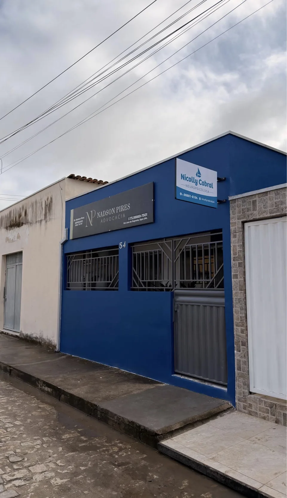 Fachada azul da clínica, no número 54, com a placa Nicolly Cabral